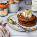 Pancakes dietetici di albumi con formaggio spalmabile e colata golosa di crema al pistacchio proteica, sopra granella di pistacchi.